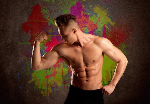 Strong guy with colorful paint wall and weight