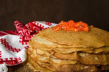 Traditional Russian pancakes with red caviar on wooden rustic background. Maslenitsa.