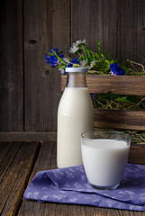 A bottle of rustic milk and glass of milk on a wooden table