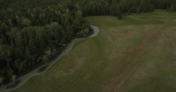 Flying in cloudy weather over the river, forest and mountains