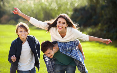 Happy girl with two boys posing in fall park