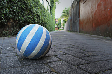 The blue and white soccer ball on the cobblestone road was forgotten by children, Kuta, Bali, Indonesia
