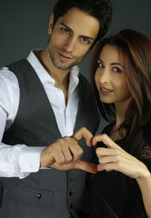 smiling couple forming hearts shape with their fingers hands
