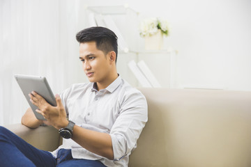 asian young man using tablet pc at home