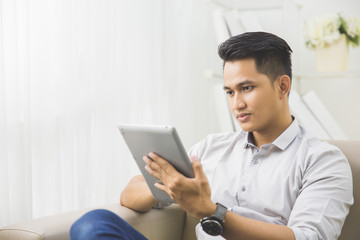 asian young man using tablet pc at home