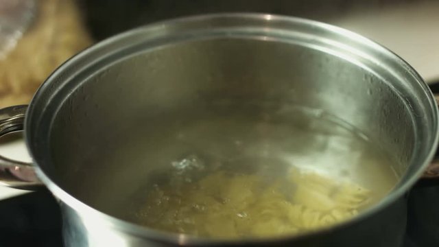 Boiling spiral pasta in the water in a metal pot 