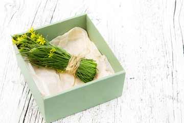bouquet of small yellow flowers in a box on a wooden background