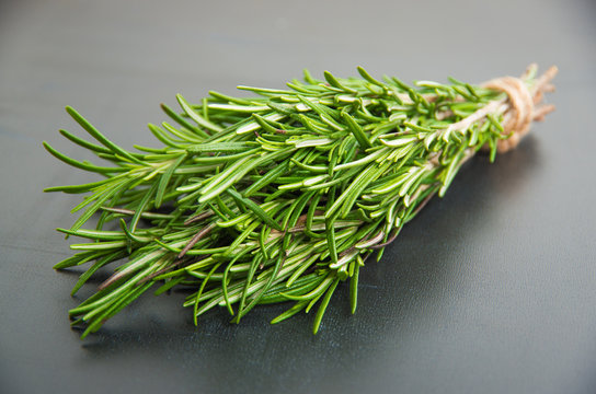 Sprigs of rosemary tied with string on a dark gray background.