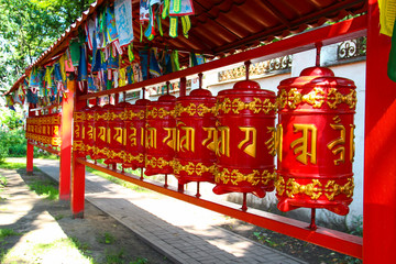 Red buddhist prayer wheels with gold text of the prayers in Sanskrit