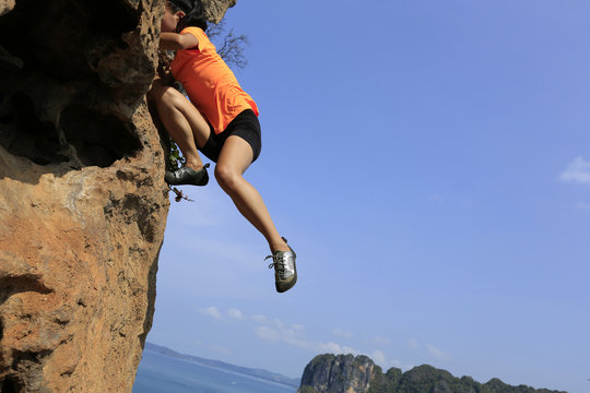 young woman rock climber climbing at seaside mountain rock