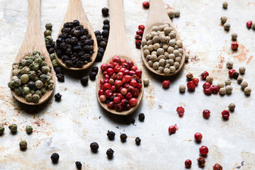 color peppercorn seeds on wooden spoons