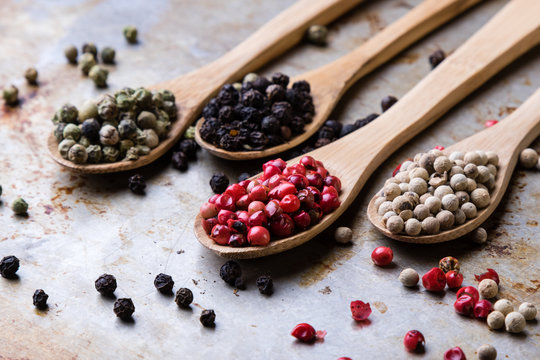 color peppercorn seeds on wooden spoons