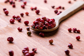 red peppercorn seeds on wooden table