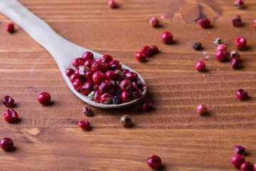 red peppercorn seeds on wooden table