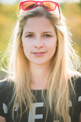 Close up outdoor portrait. Blonde woman posing outdoor. Looking at camera.