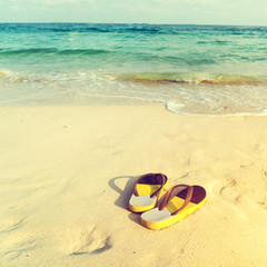 Fototapeta na wymiar retro slippers on tropical beach in summer - vintage color tone effect