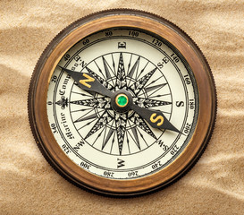 Vintage brass compass on sand