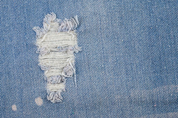 Blue jeans background closeup view to torn texture.