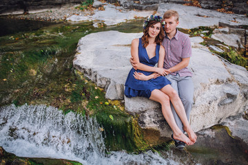 Beautiful young couple embracing near the river and stones