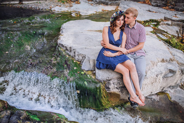 Beautiful young couple embracing near the river and stones