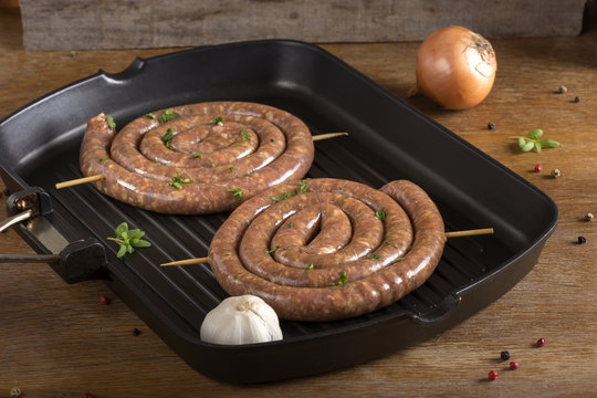 Raw sausages on a grilled pan