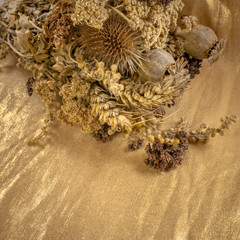 bouquet of dried flowers on a background of gold colored cloth, beautiful background for your concept or project