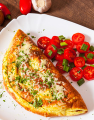 omelette with cheese and salad in a plate on wooden table