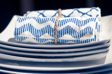 Blue napkin and empty white plate on blue tablecloth