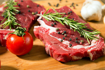 Raw beef steak on  wooden table with vegetables