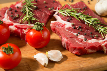 Raw beef steak on  wooden table with vegetables