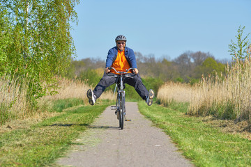 Senior fährt Rad mit abgespreizten Beinen, Spaß haben in der Natur