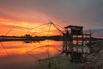 Fototapeta na wymiar Silhouette abandoned house on lake with fishing net