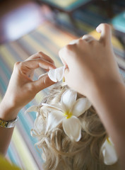 Beautiful, cute blond bride doing hair with flowers on wedding day.