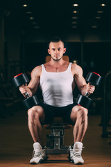 Fototapeta na wymiar sport, bodybuilding, weightlifting, lifestyle and people concept - young man with dumbbells flexing muscles in gym