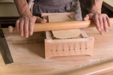 Preparing homemade pasta on wooden table using rolling pin