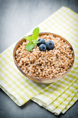Buckwheat porridge in a bowl with mint leaves and blueberries.