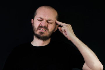 Serious man with beard and mustaches on black background in low key, frustration and despair gesture 