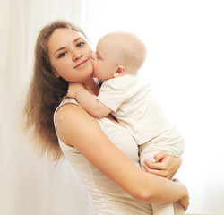 Happy young mother with her baby on hands over window