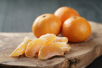 ripe tangerines peeled on wood table, selective focus