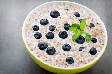Buckwheat porridge in a bowl with mint leaves and blueberries.