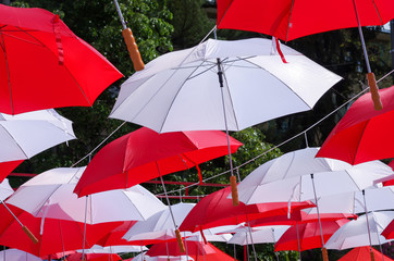 Hanging Multicoloured umbrellas over blue sky. Red and withe large size umbrellas onto the blue sky. 