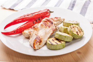 grilled chicken with vegetables on wooden table