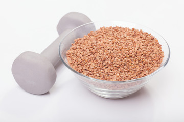 dish of buckwheat porridge near dumbbell isolated on white background