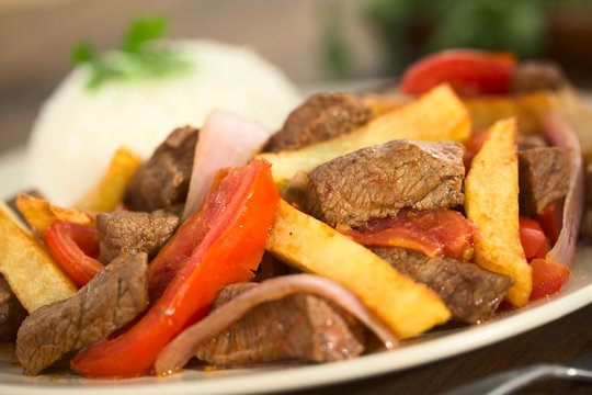 Peruvian dish called Lomo Saltado made of beef, tomato, red onion and French fries, served with rice (Selective Focus, Focus one third into the dish)