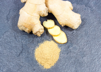Raw ginger and ginger powder on a black background