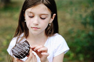 Cute kid girl eating sweet donuts