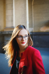 Beautiful young blond girl with glasses in the street.