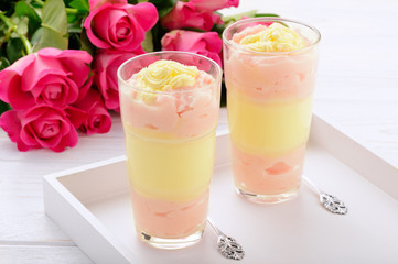 Raspberry and vanilla pudding in glasses on white wooden tray.