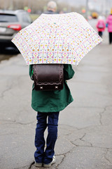 Kid girl with umbrella walking in city street