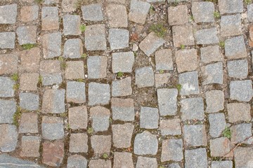 Old stone paving on the street. Detail of historic granite tiles.
